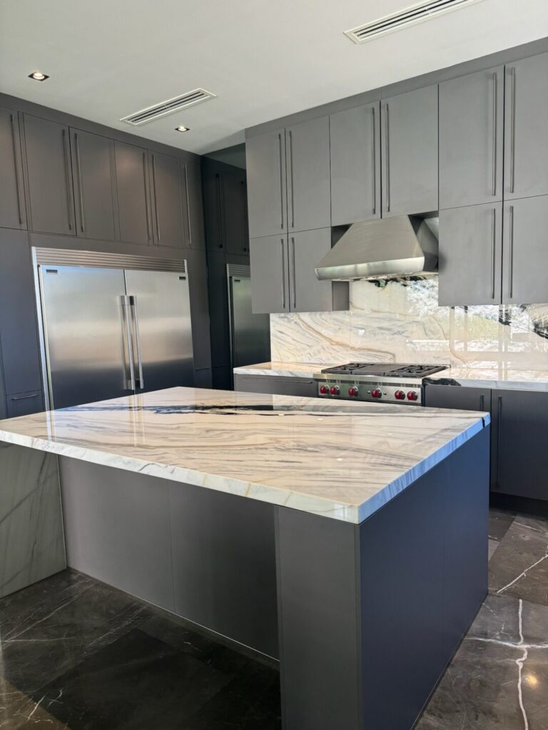 A marble countertop on a kitchen island with cupboards in the background
