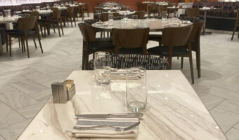 A restaurant with round and square marble table tops.